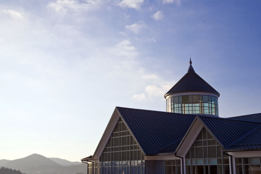 Campus building with glass tower roof set against mountains under a clear sky